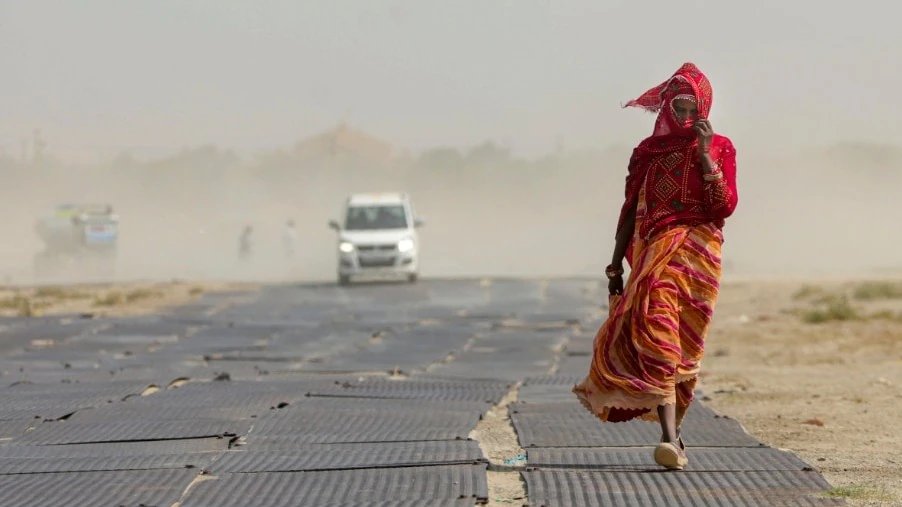 आसमान से बरसती आग के बीच सड़क पर चलती महिला. (PTI Photo)